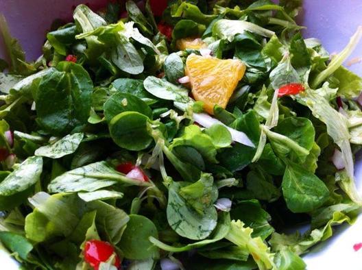 My lunch salad - corn salad and other tender greens, an orange, a tomato and some different kinds of radishes